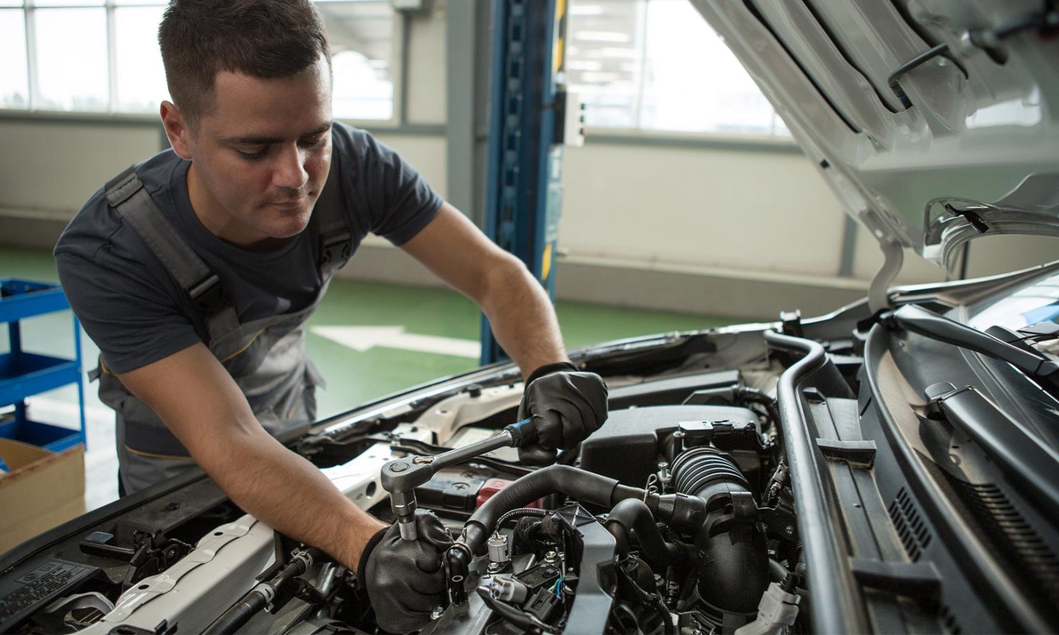 A Noted Automotive technician at work under the hood of a car in the Boynton Beach shop